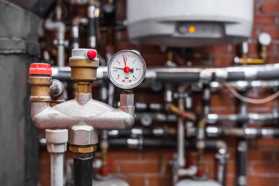 Un manomètre à pression muni d'une soupape de sécurité automatique sur le tuyau sur fond d'un système de chauffage d'une entreprise industrielle