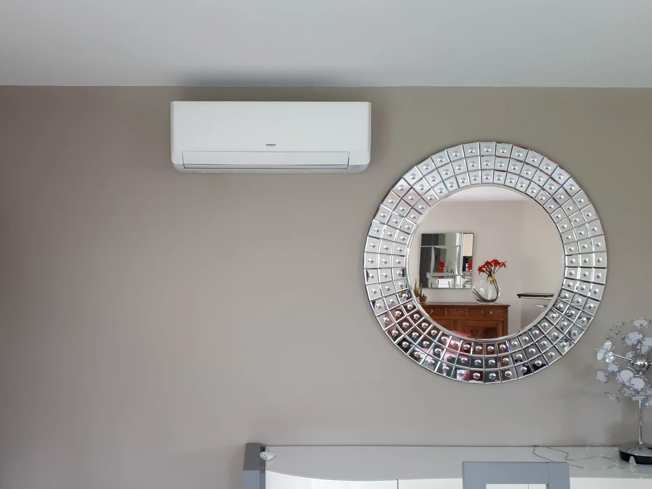 Intérieur d'habitation avec cheminée ancienne en pierre sculptée et poêle à granulés moderne blanc et noir en fonctionnement