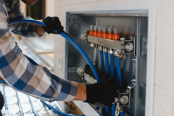 Plombier professionnel en uniforme travaillant dans une salle de bain moderne blanche