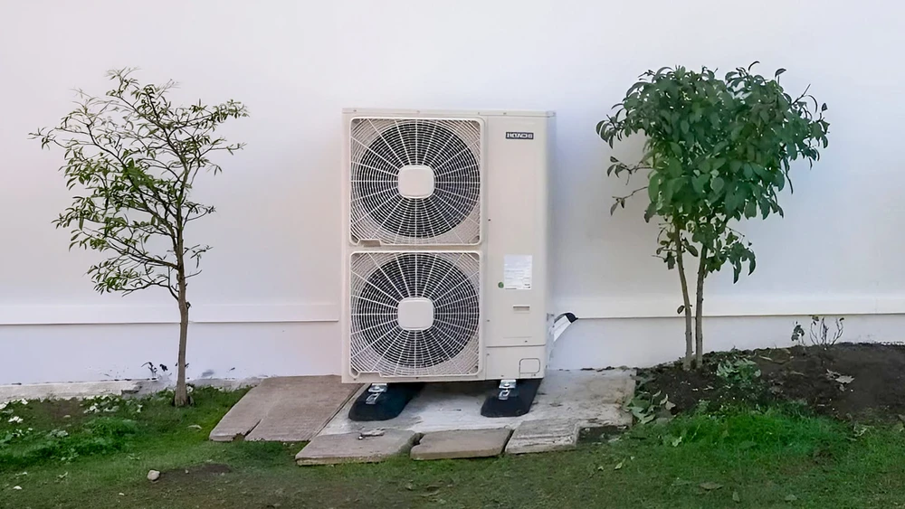 Extérieur résidentiel avec unité de climatisation posée sur carrelage beige contre mur blanc