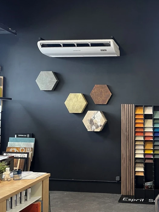 Unité extérieure de climatisation installée sur terrasse béton contre mur blanc