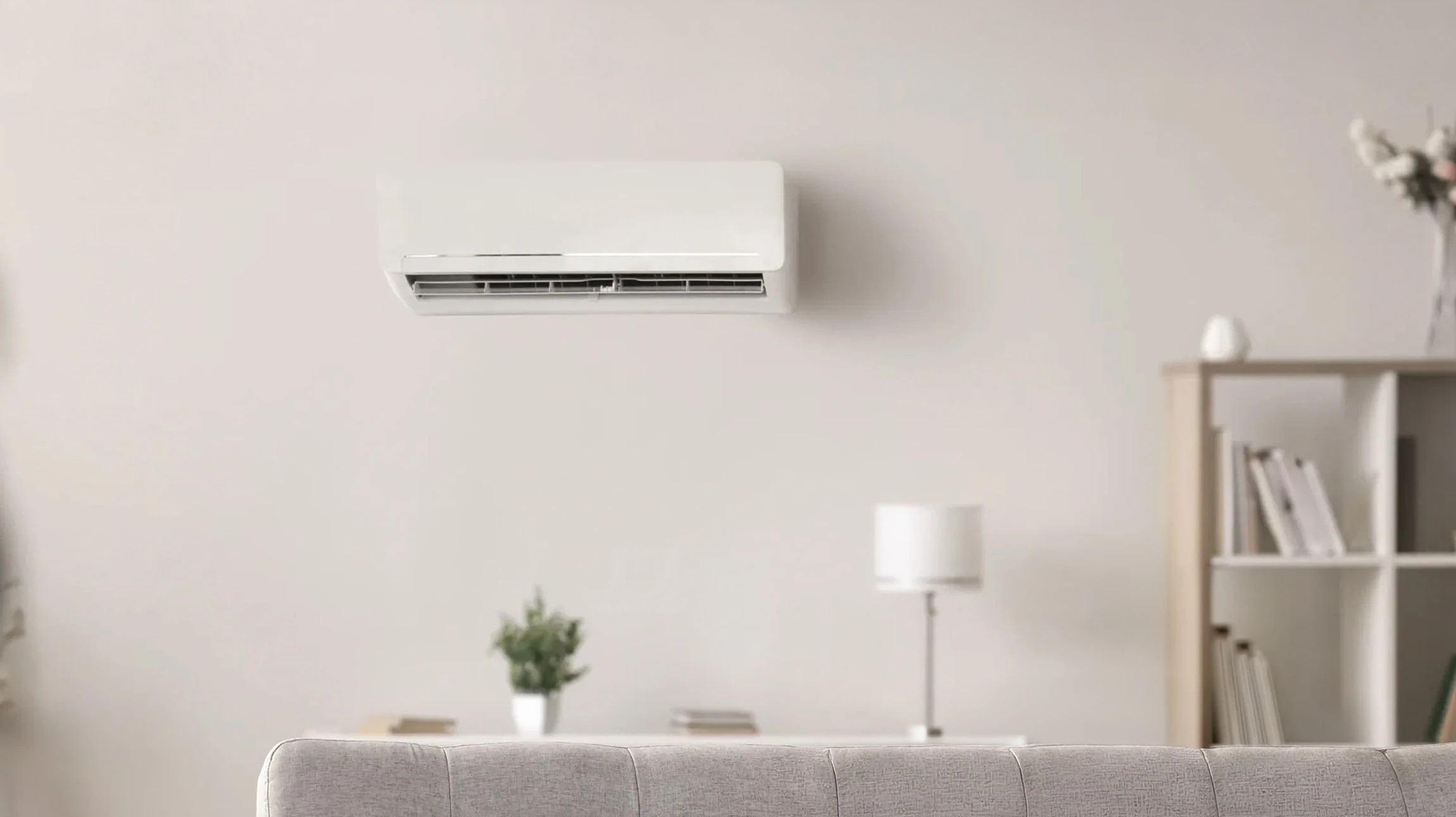 Une femme se détend dans un salon moderne sous un climatiseur mural en fonctionnement, diffusant de l'air frais visible