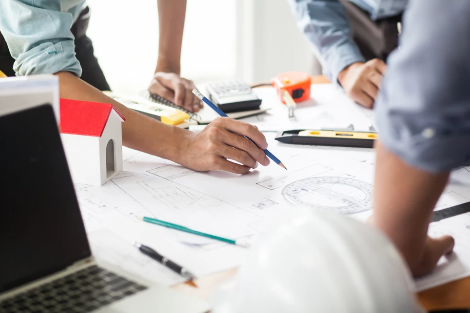 Plombier en salopette rouge travaillant dans une salle de bain moderne, agenouillé près d'un meuble vasque gris